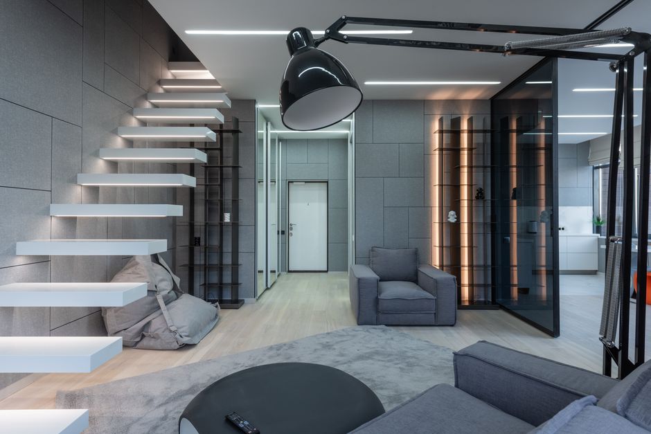 Interior of modern apartment with white steps near armchair and carpet with table near bean bag chair and lamp near shelves and door