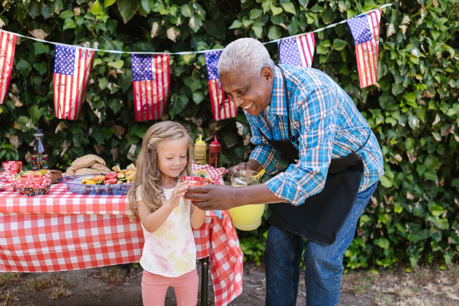 An outdoor family picnic with American flag decor and food, showcasing a joyful celebration.