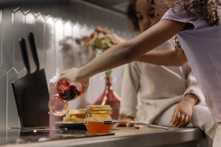 Two children making jam sandwiches together, fostering teamwork and fun in the kitchen.