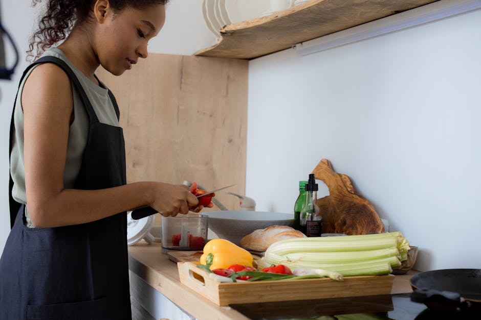 A woman slicing vegetables on a kitchen counter, preparing a meal in a modern setting.
