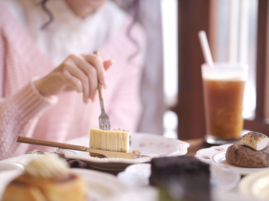 A person enjoying cake and iced coffee in a cozy cafe setting, evoking warmth and relaxation.