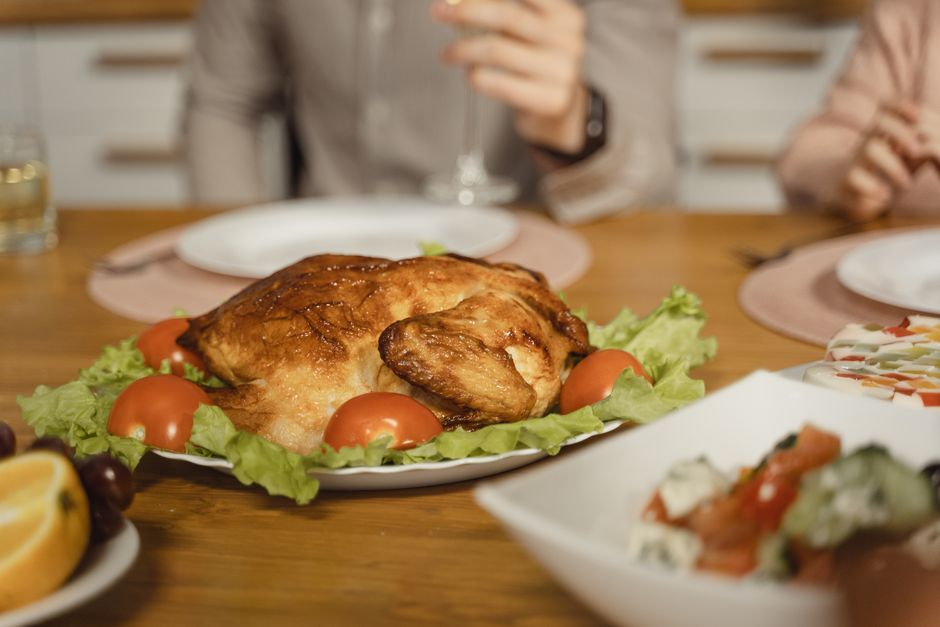 A delicious roasted chicken served on a festive dinner table with a variety of side dishes.