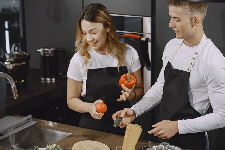 Young couple preparing meal in a modern kitchen, smiling and enjoying time together.