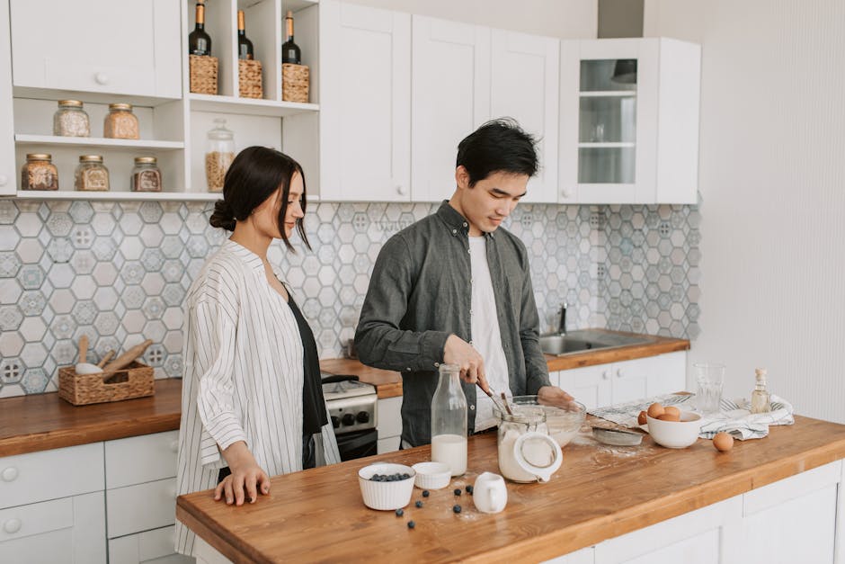 A couple in a modern kitchen preparing a meal together, showcasing teamwork and togetherness.