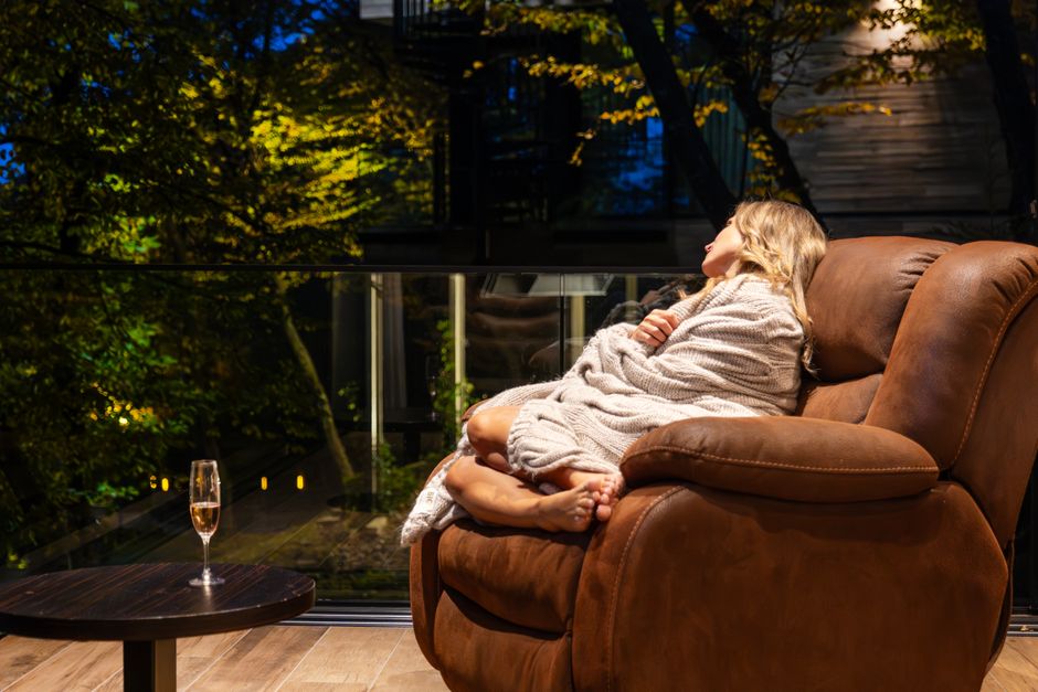 Woman relaxing on a balcony in Tbilisi, Georgia, wrapped in a blanket, enjoying the serene evening.