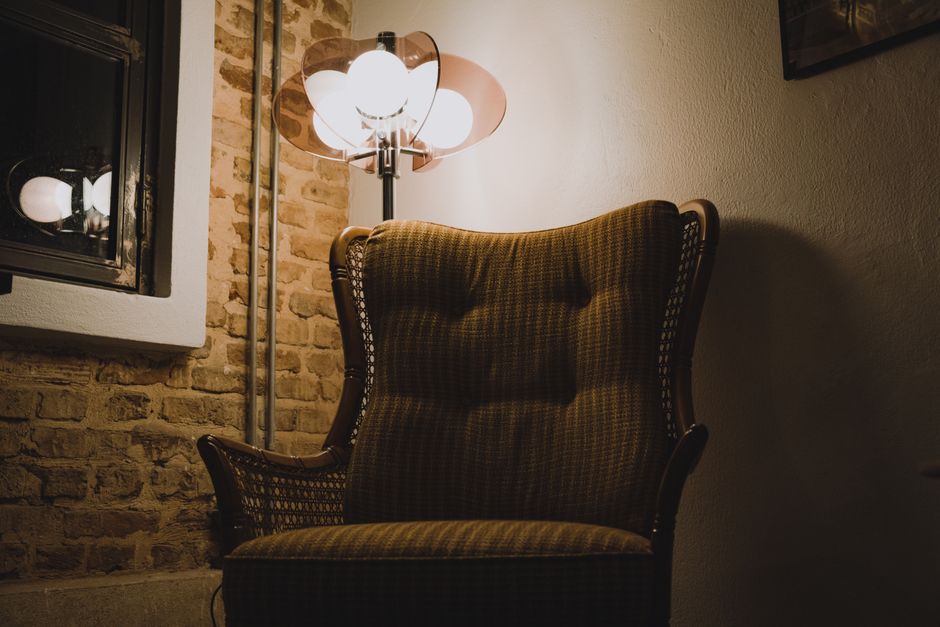 Warm ambient light illuminating an antique chair against a rustic brick wall in Istanbul.