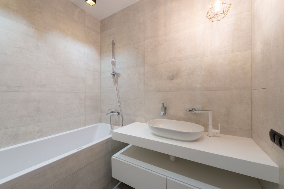 Elegant minimalist bathroom featuring a sleek bathtub and contemporary sink setup.