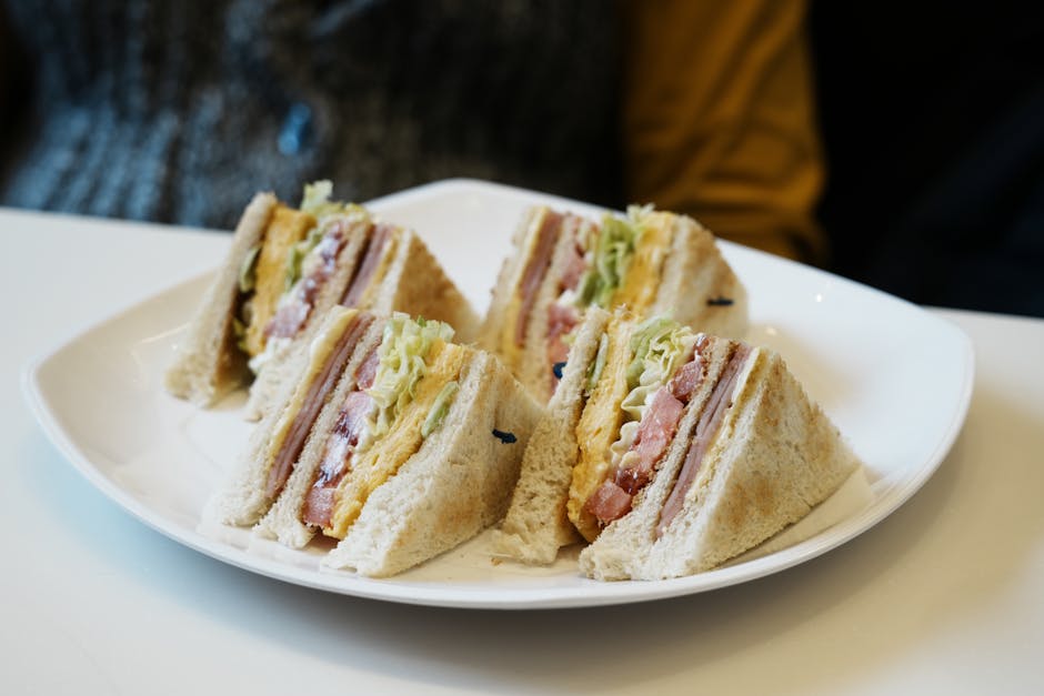 Close-up of club sandwiches with ham, cheese, and veggies on a plate.