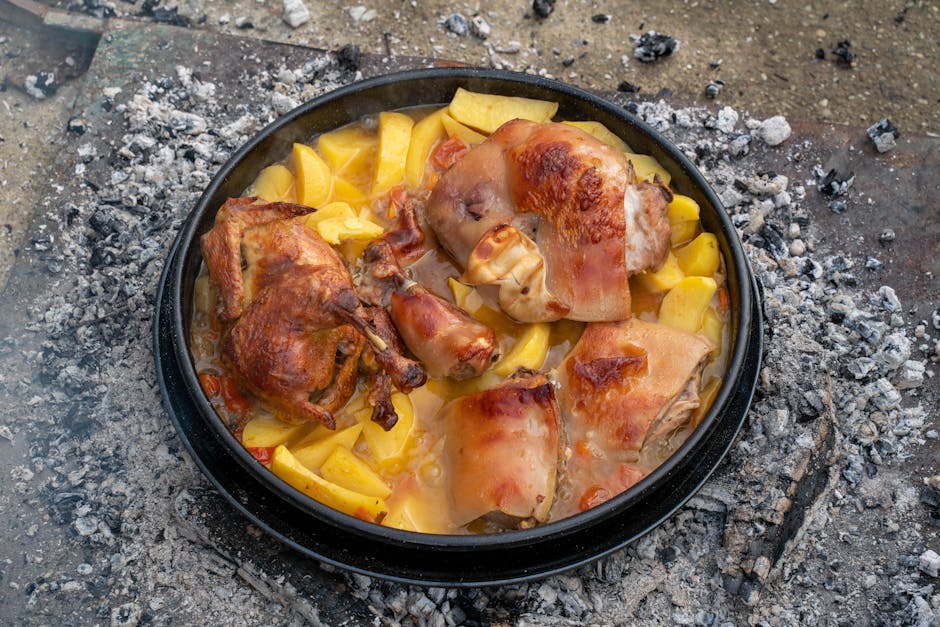 A delicious rustic dish of roasted pork and potatoes cooked outdoors over campfire embers.