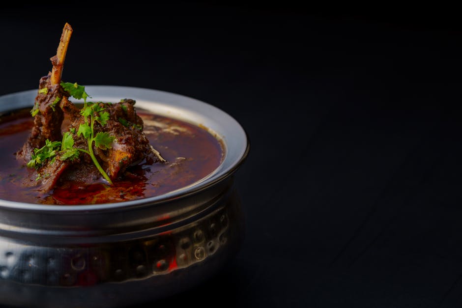 Delicious Indian lamb curry garnished with fresh coriander in a traditional metal bowl, perfect for food enthusiasts.