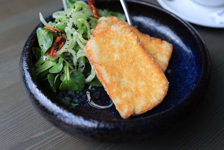 Delicious deep-fried tofu served with fresh greens and vibrant salad on a rustic plate.