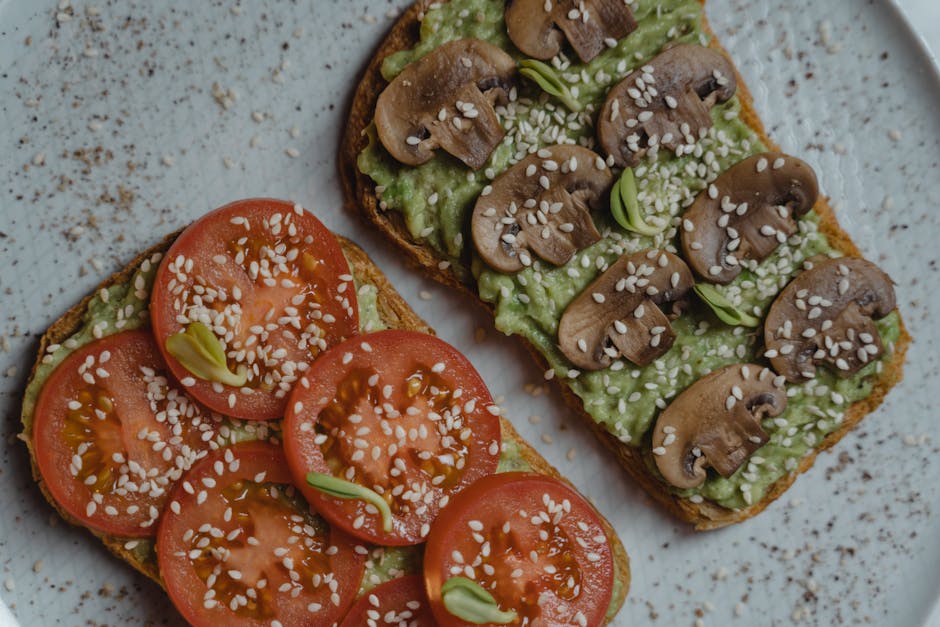 Close-up of vegan avocado toast with fresh tomatoes and mushrooms on a plate.