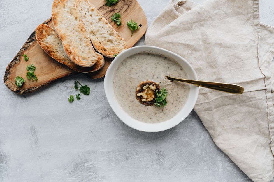 Delicious creamy mushroom soup served with toasted bread slices and fresh parsley in a rustic setting.