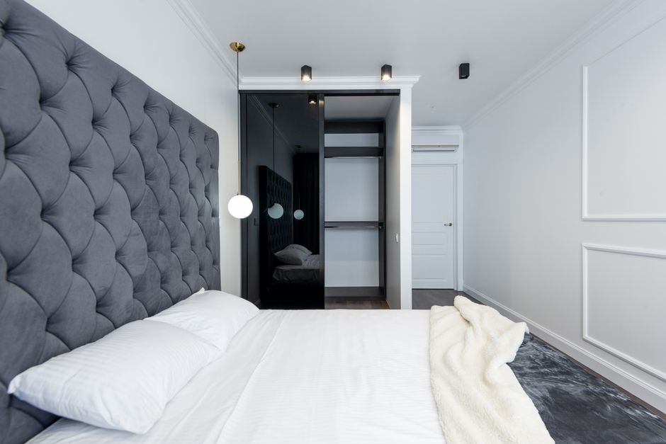 Luxurious bedroom with modern touches featuring a tufted headboard and open wardrobe.